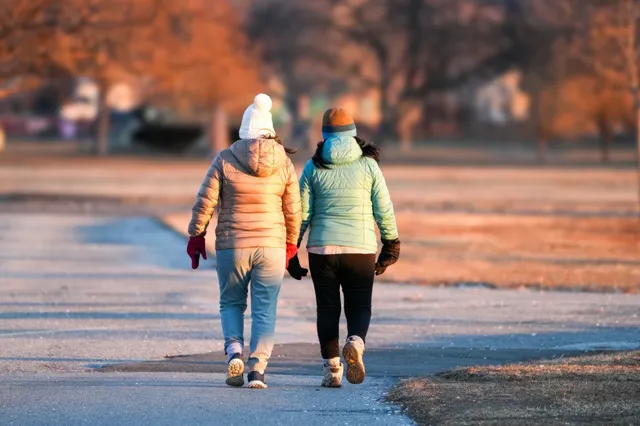 Two friends walking together outdoors on a bright afternoon