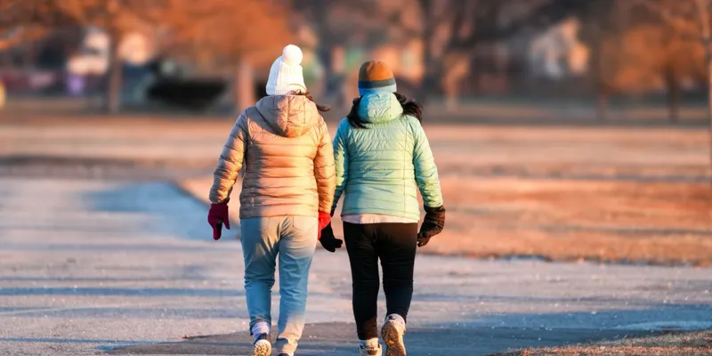 Two friends walking together outdoors on a bright afternoon