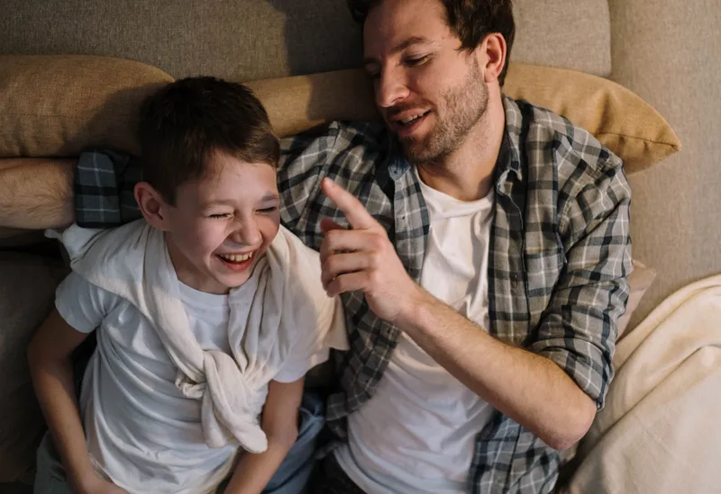 A man and a boy sharing a relaxed laugh together at home