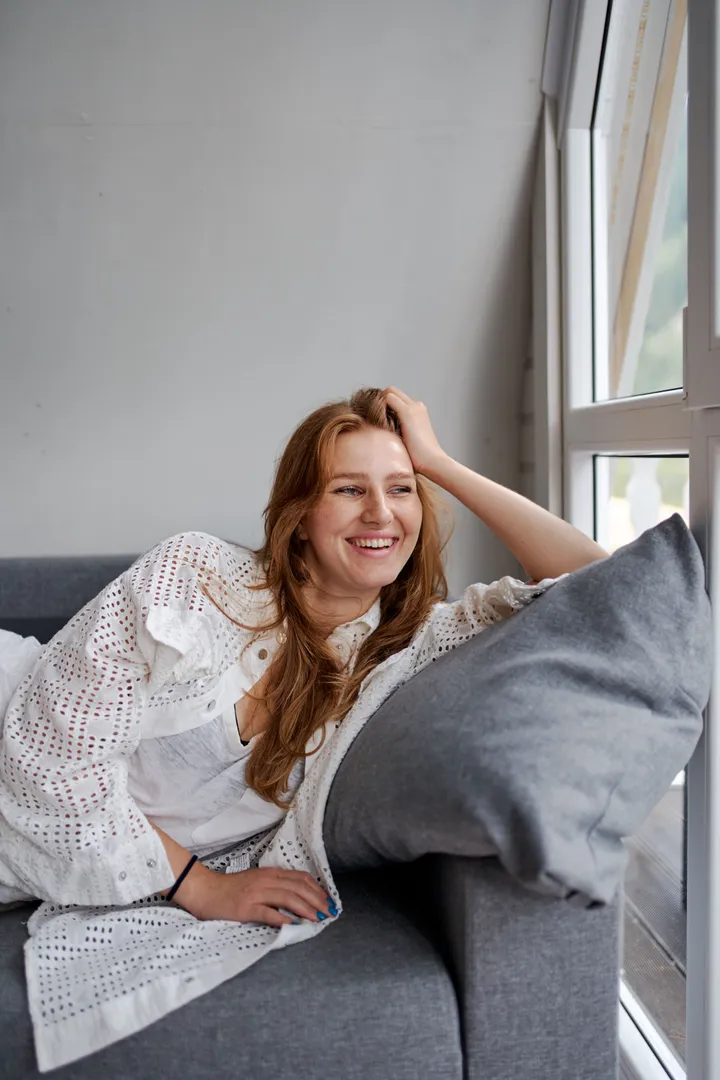 A woman relaxing on her sofa, laughing during a friendly chat
