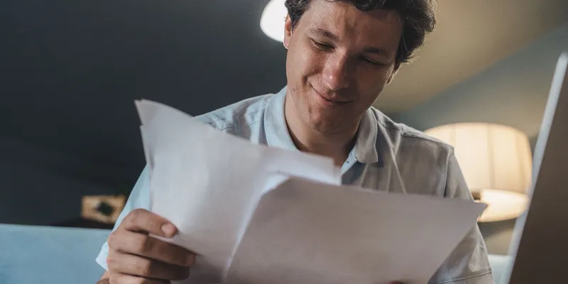 A man reading through his NDIS plan paperwork at home