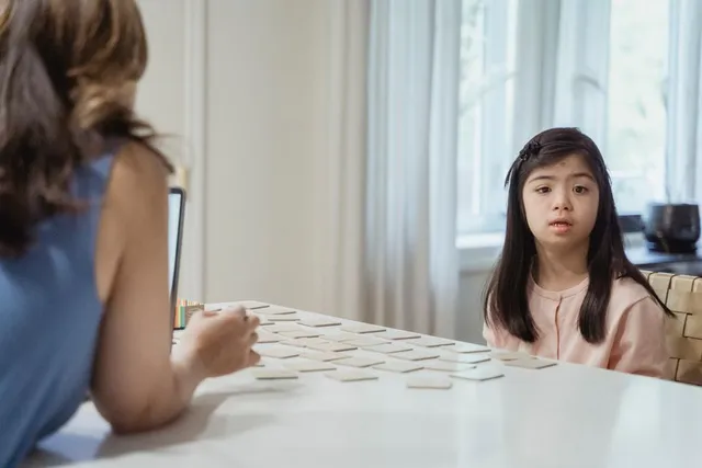 A young girl and a therapist playing a card game together at a table
