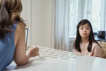 A young girl and a therapist playing a card game together at a table