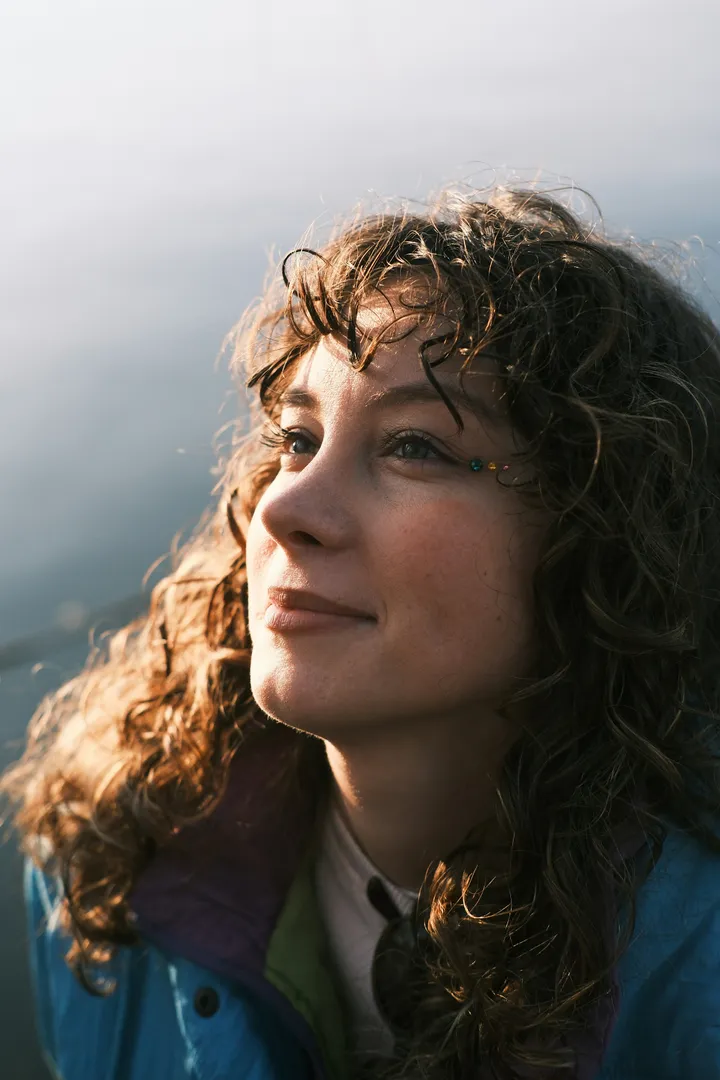 A woman with curly hair looking to the side outdoors